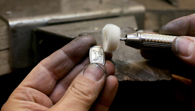 A making of image of a cufflink with a frog engraving on being polished.
